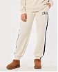 Женские спортивные штаны Hollister Dad joggers бежевого цвета с лого. Модель 06370. Подробное описание и цена товара. Доставка по России, Москве и Области от Moscow USA
